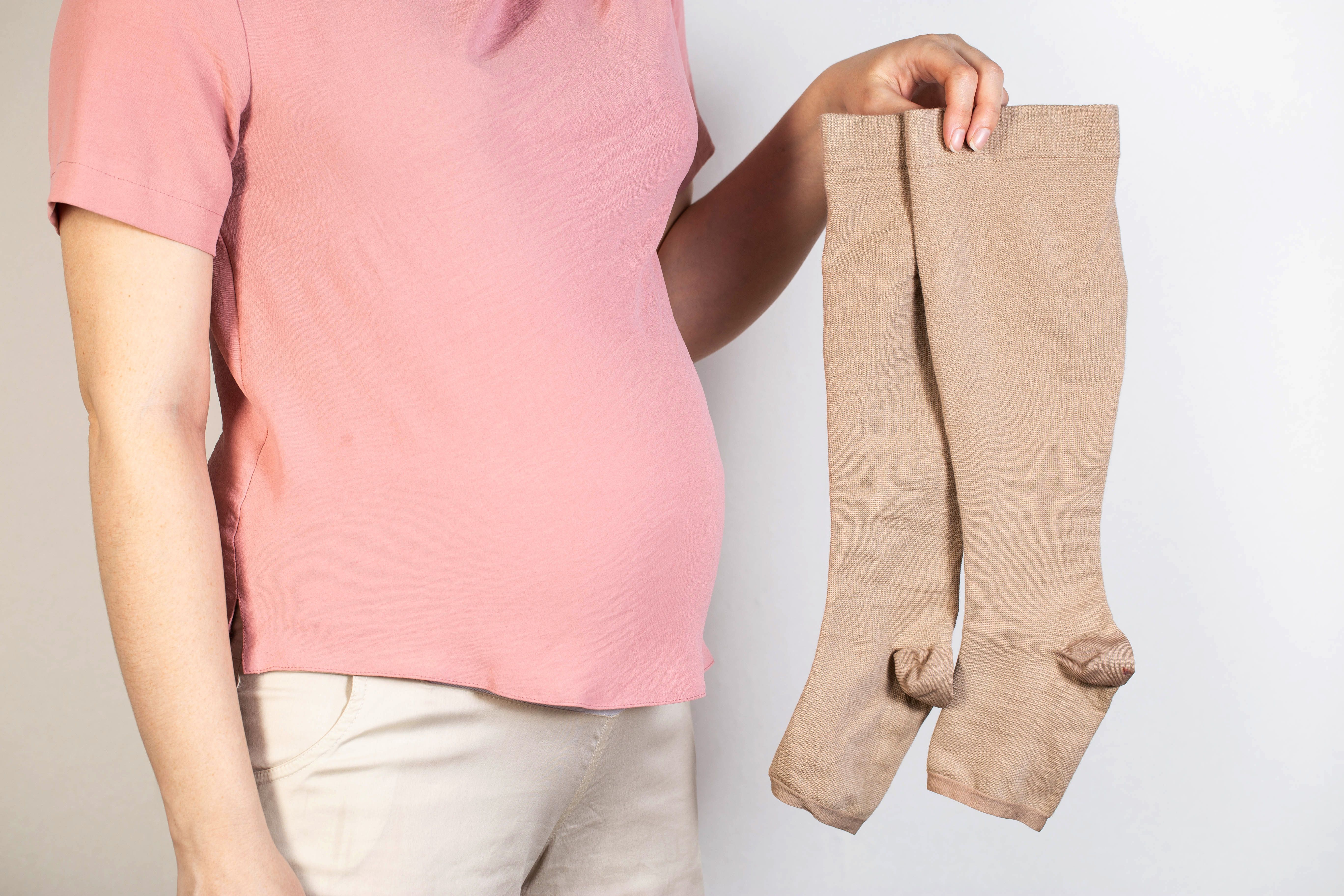 pregnant holding compression stockings