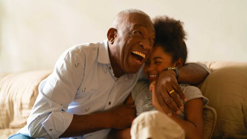 Grandfather laughing and embracing his granddaughter.