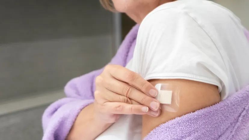 woman puts a hormone patch on her arm to treat menopause