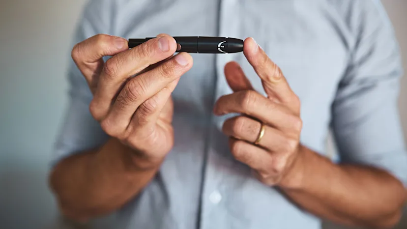 Man testing his blood sugar with a finger prick machine.