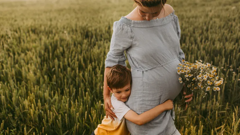 Pregnant mother walking through a field with her son.