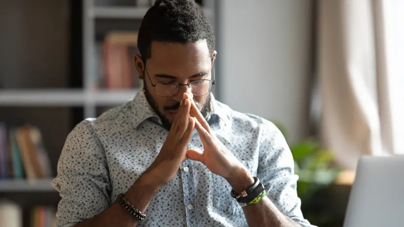 Man with irritable bowel syndrome sitting at his desk with some stomach pain.