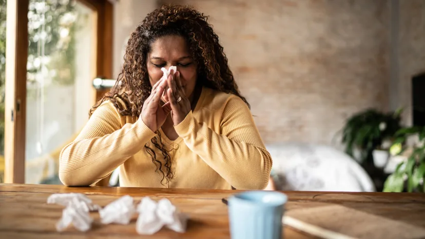 Woman with a sinus infection blowing her nose.