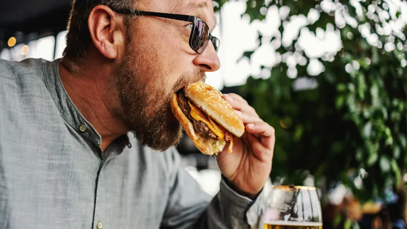 Man eating a greasy cheeseburger.