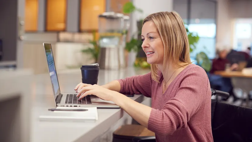 Woman with multiple sclerosis working on a laptop in the office.