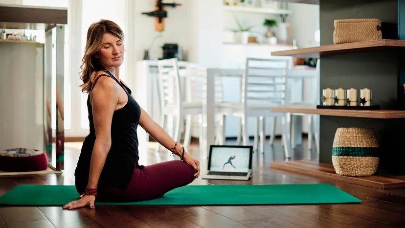Woman following a yoga instructional video in her living room.