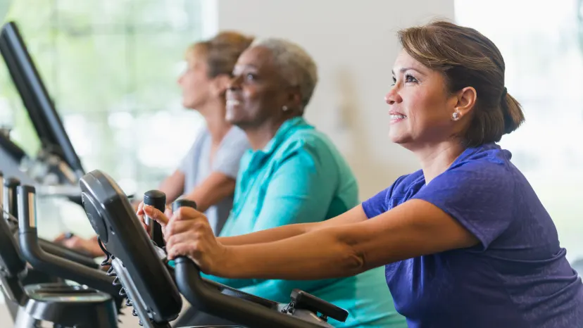 Mature woman on a spin bike exercising to manage arthritis symptoms