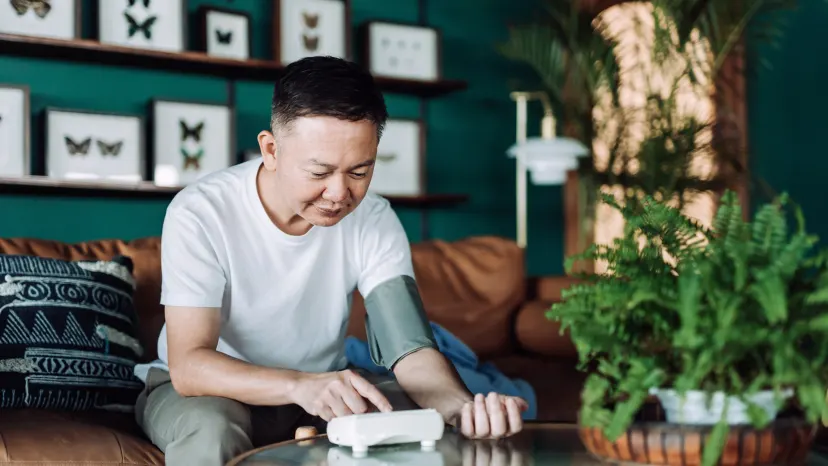 man sitting on his couch with a blood pressure cuff on his arm 