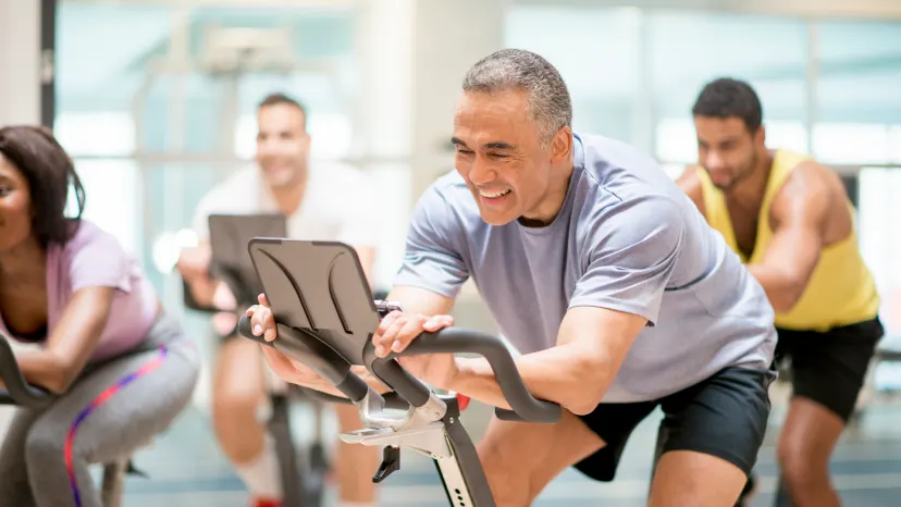 Man on a spin bike in a group class exercising to control hypertnesion
