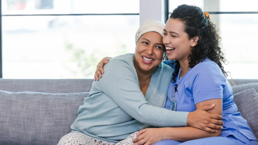 Smiling woman with ovarian cancer hugging a nurse