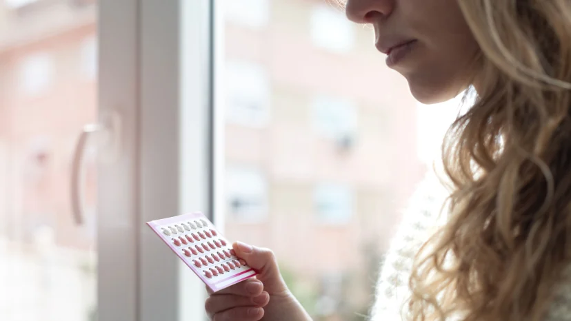 Woman holding a card of birth control pills to help prevent ovarian cancer
