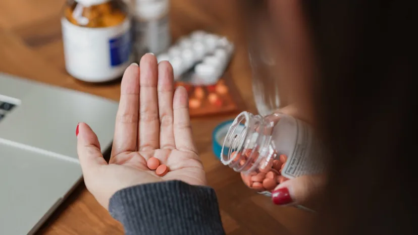 Woman taking ibuprofen tablets that can cause peptic ulcers