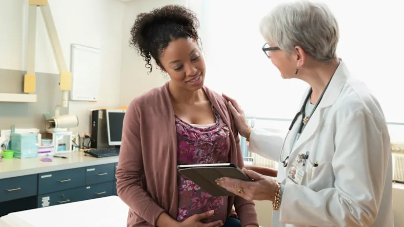pregnant woman speaking with her doctor in exam room