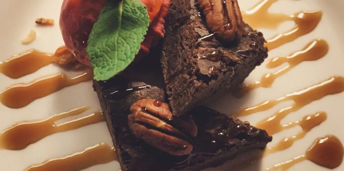2 stukjes brownie op een bord met daarbij een munt blaadje