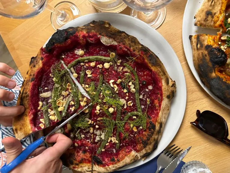 Iemand die met een schaar in de pizza knipt