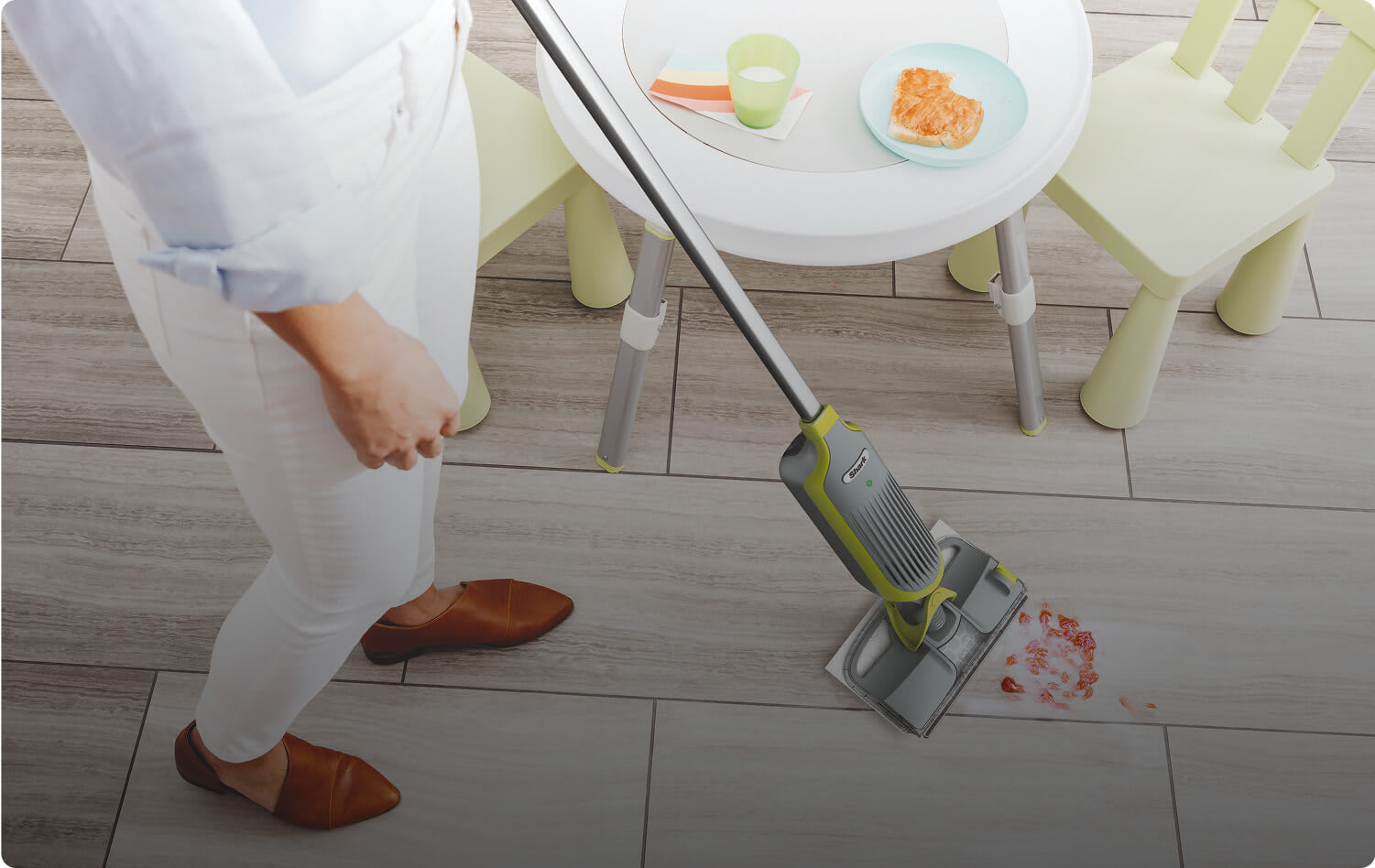 A person using the Shark 2-in-1 Cordless VacMop to clean up a food spill on the kitchen hard floor.