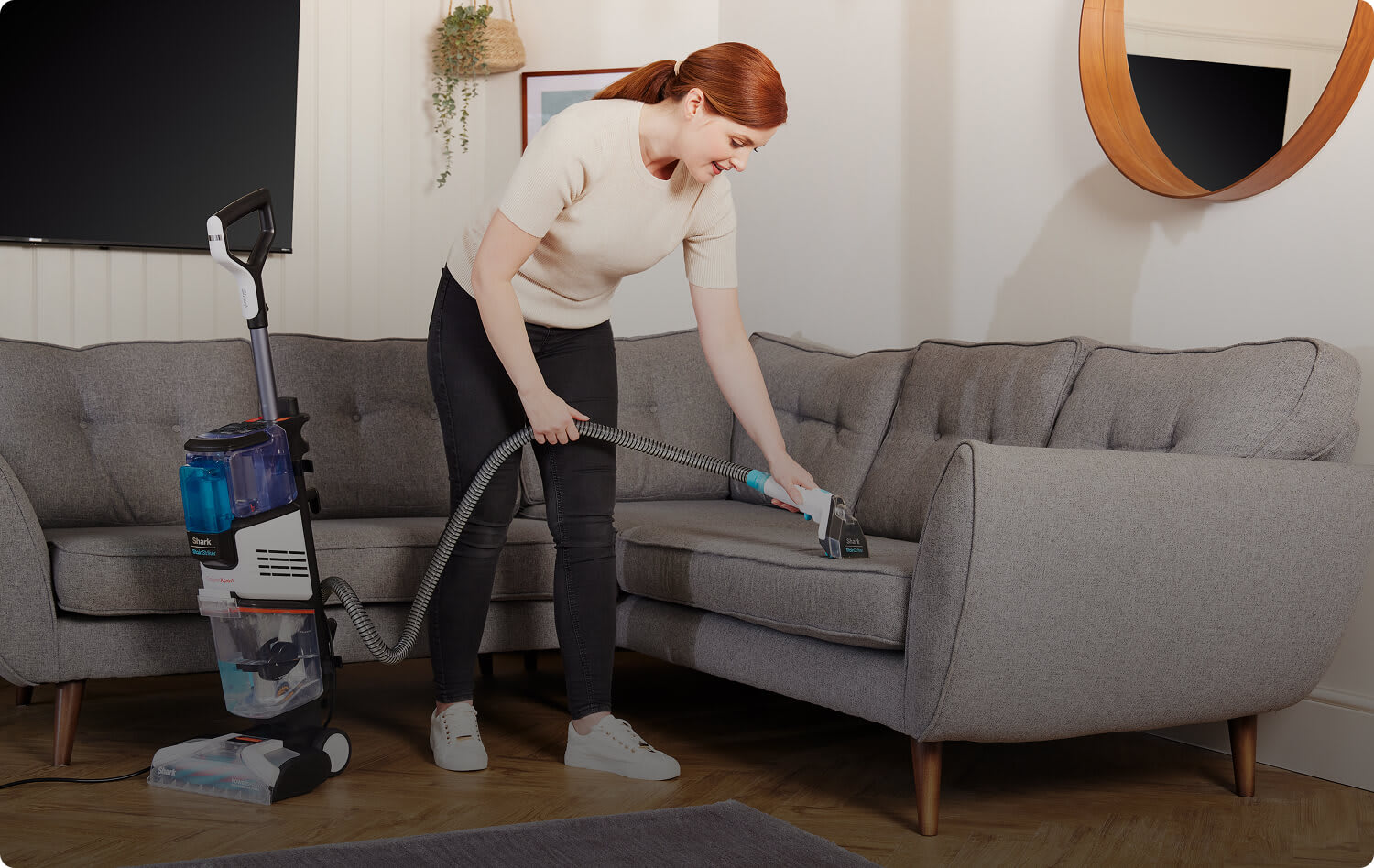 A women using the built-in StainStriker on the Shark CarpetXpert to clean a sofa