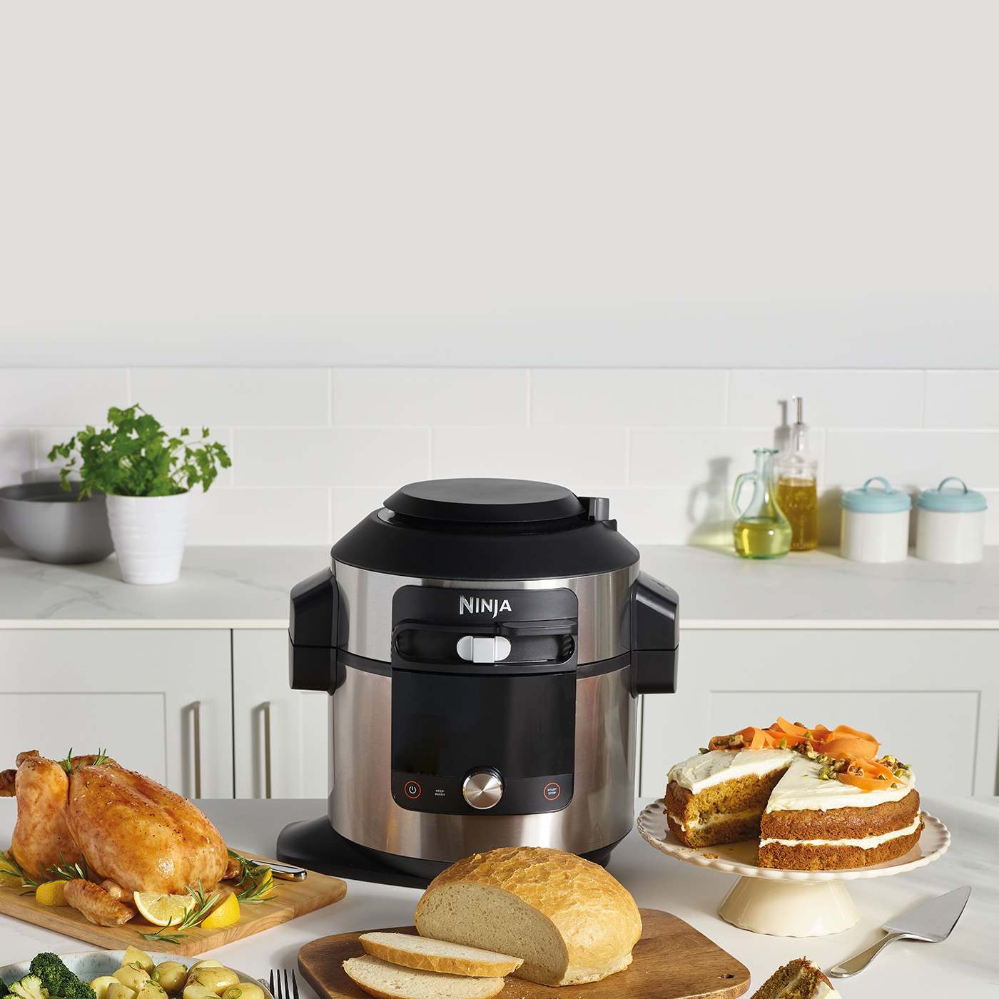 Ninja Kitchen Multicooker op een witte tafel met een paar borden eten