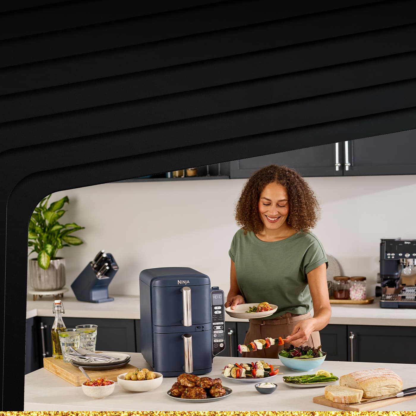 Afbeelding van een Ninja keuken airfryer met wat gekookt eten ernaast en een grijze keukenmuur.