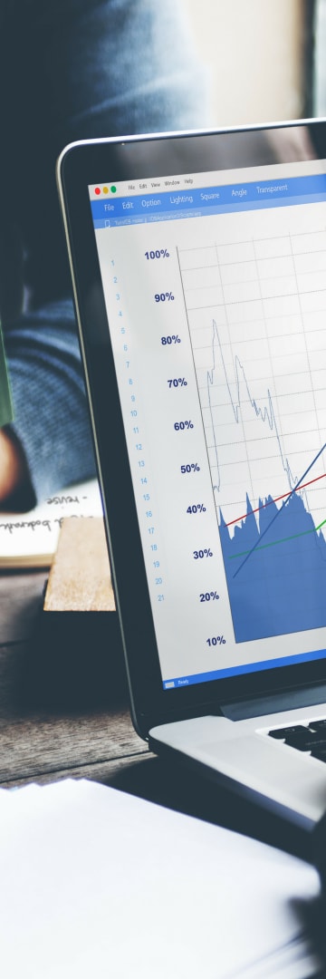 Charts, data on laptop, person holding book