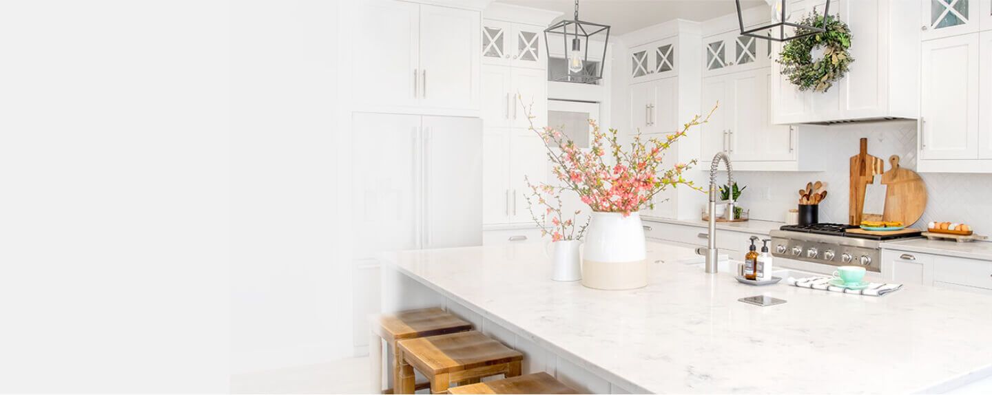 Clean white kitchen with white table which has white porcelain vase on it