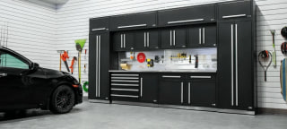 Well organized garage with large garage cabinet storage next to black car