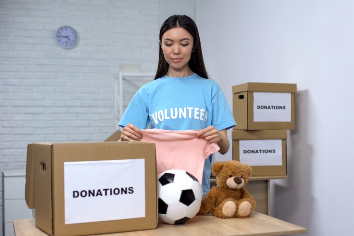 Young woman organizing clothing as part of kids closet ideas