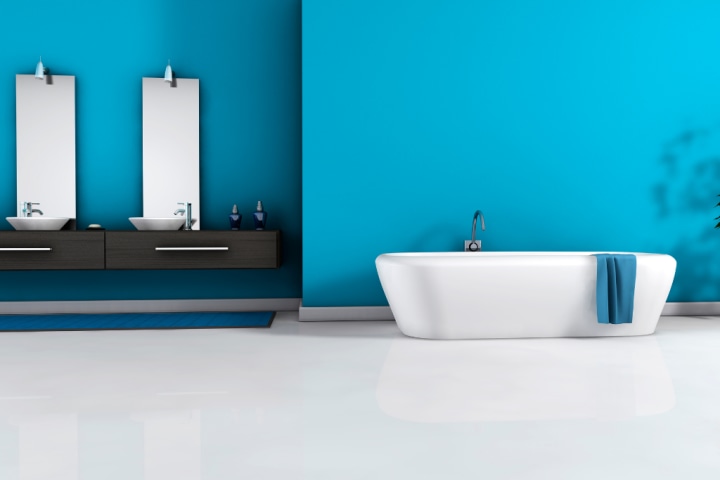 Blue bathroom walls with a black drawer vanity counter, white sinks and bathtub.