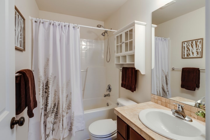 a white bathroom in a modern cottage style showing shelving fixed to the wall above the toilet for Small bathroom design ideas