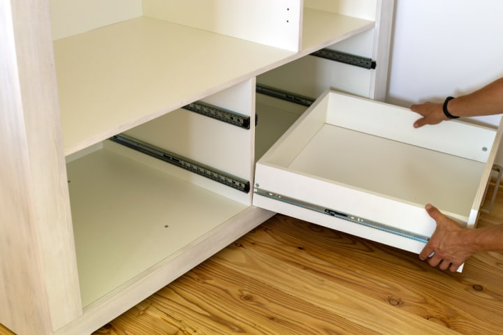 Close up of wooden drawer box and front being installed in contemporary cabinet