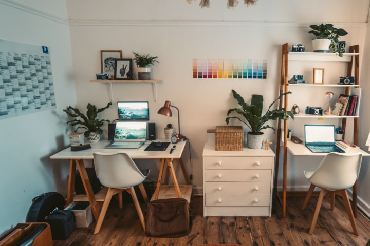 Two white desks with shelving and laptops