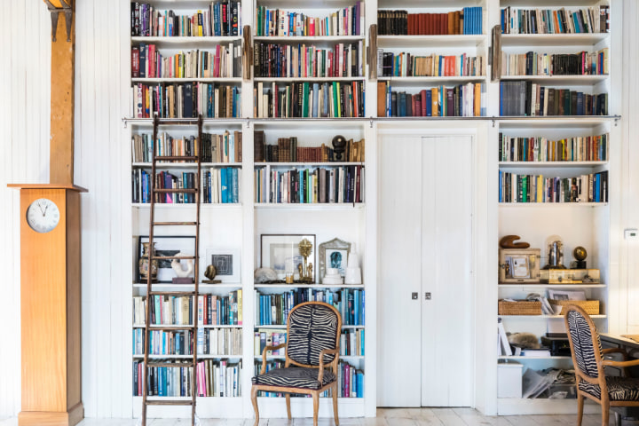 Large built-in white bookcase filled with colorful books for home office storage ideas