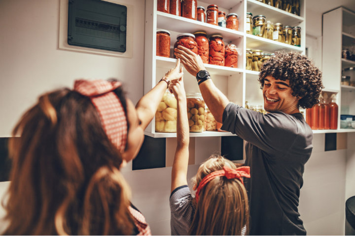 Man with children taking jars with pickled vegetable from pantry