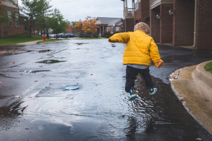 Young boy wearing yellow coat playing in the rain