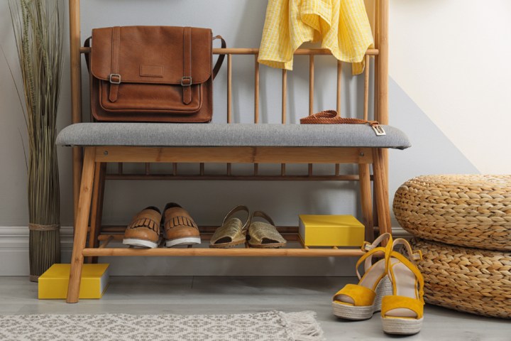 Shoes resting on the bottom shelf of a wooden bench 