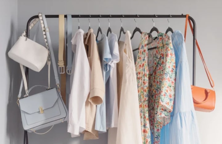 clothes rack with handbags, belts, and shirts hanging on it