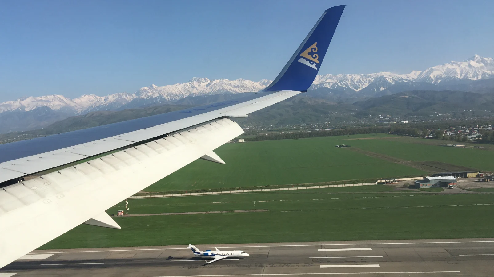 Air Astana landing in Almaty, Kazakhstan, with Alatau Mountains in the background