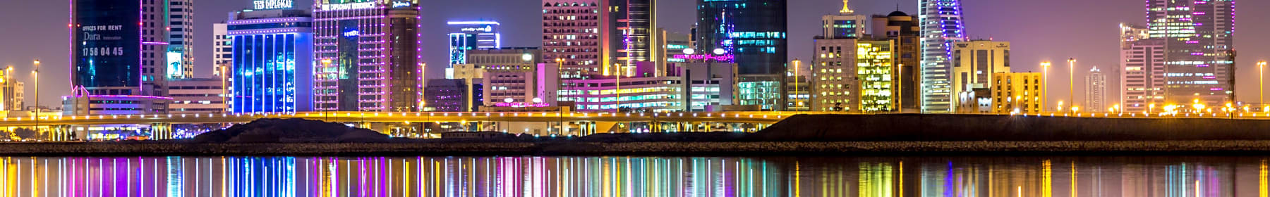 A view of the skyline of Manama, capital of Bahrain with the World trade Center building at night and water reflection after removals to Bahrain