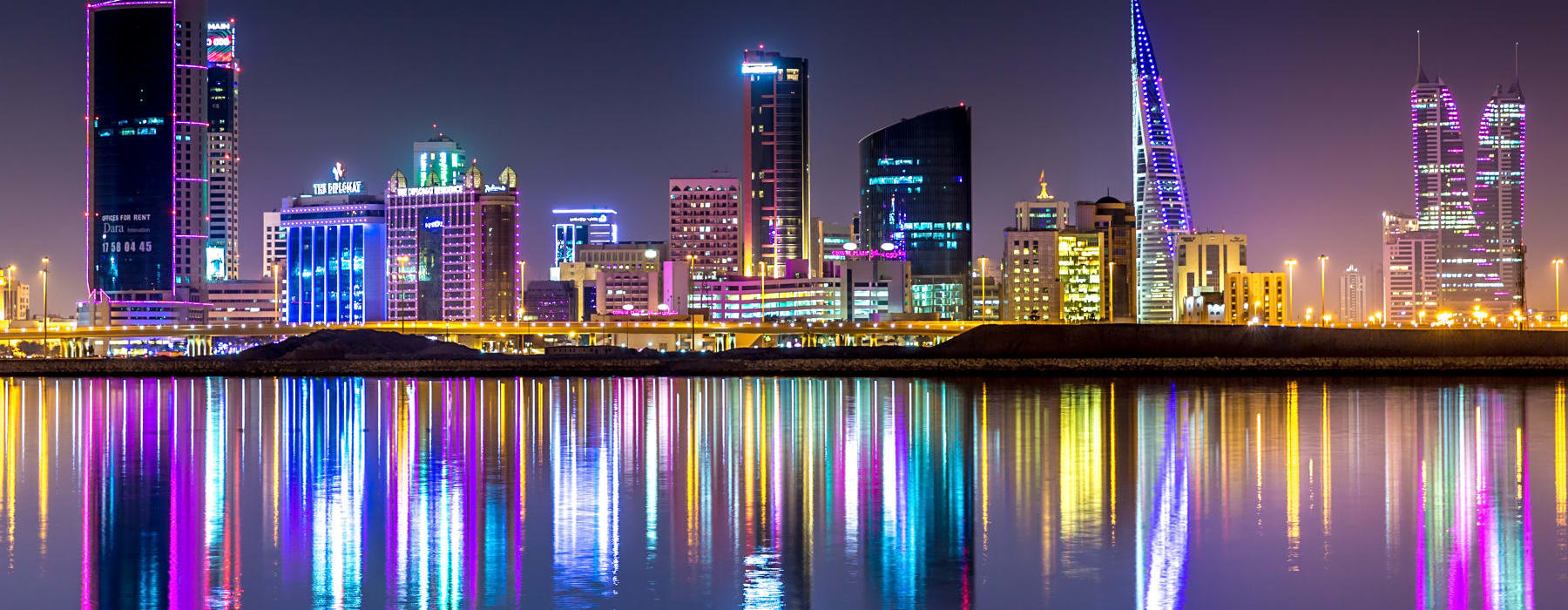 A view of the skyline of Manama, capital of Bahrain with the World trade Center building at night and water reflection after removals to Bahrain