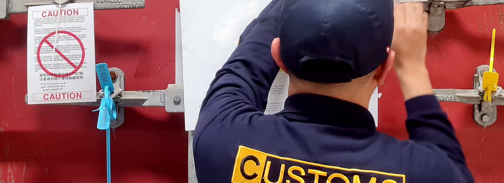 A customs officer inspecting the door of an international shipping container