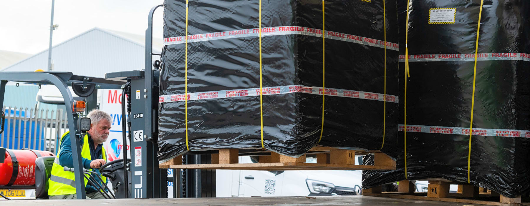 A man in a forklift loading a 1st Move International pallet on to a container transport vehicle for shipping overseas