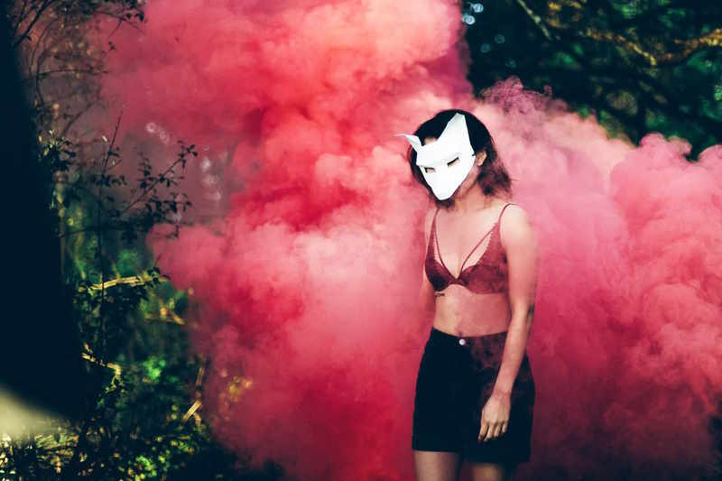 Mystische Frau mit Maske kommt aus einer roten Wolke