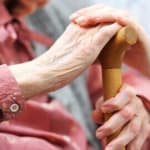 Woman holding cane while sitting