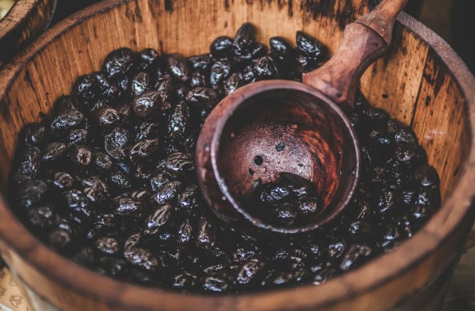 A wooden bucket and ladle of cocoa beans
