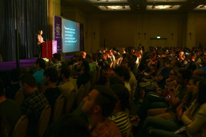 Sia speaking at a podium in front of a large crowd
