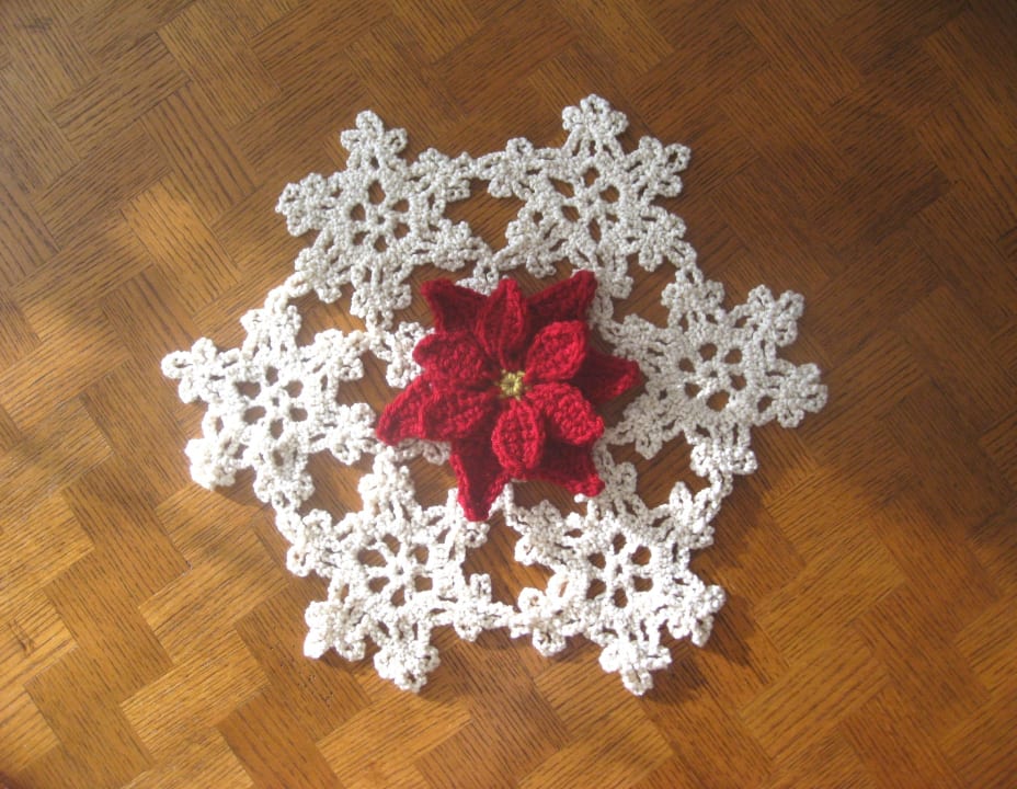 Crochet poinsettia sitting on top of the crochet snow flake