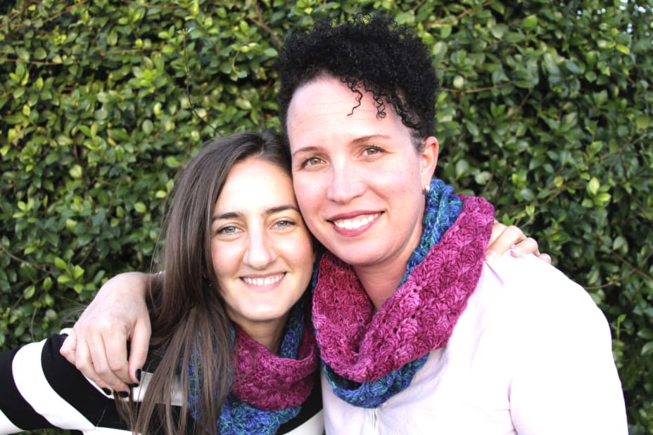 Two friends hugging with matching crochet cowls