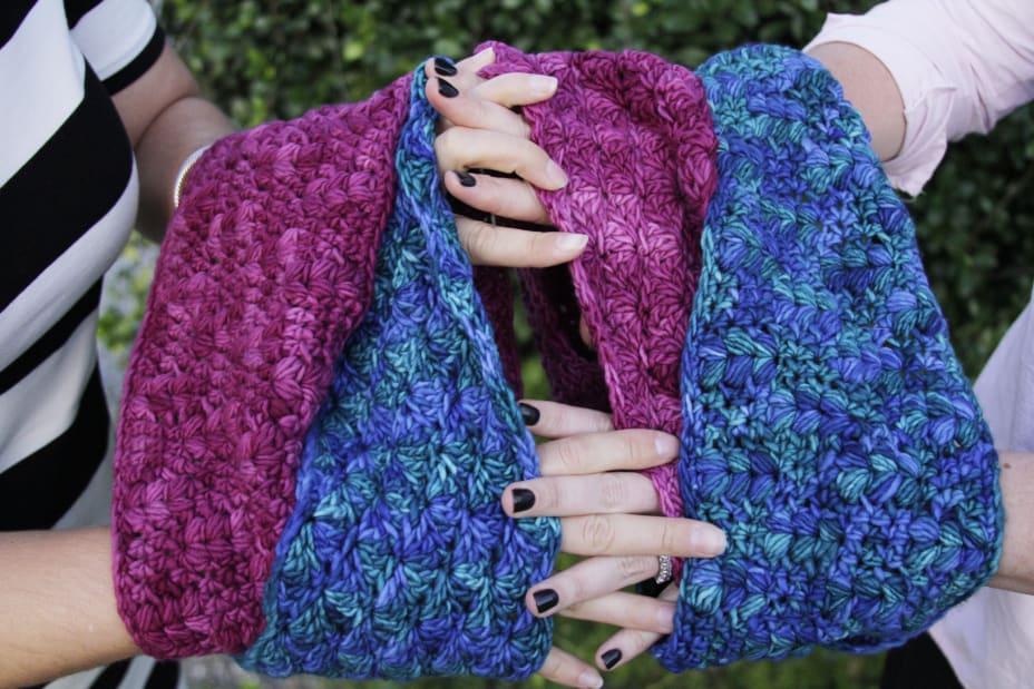 Women holding hands through matching cowls