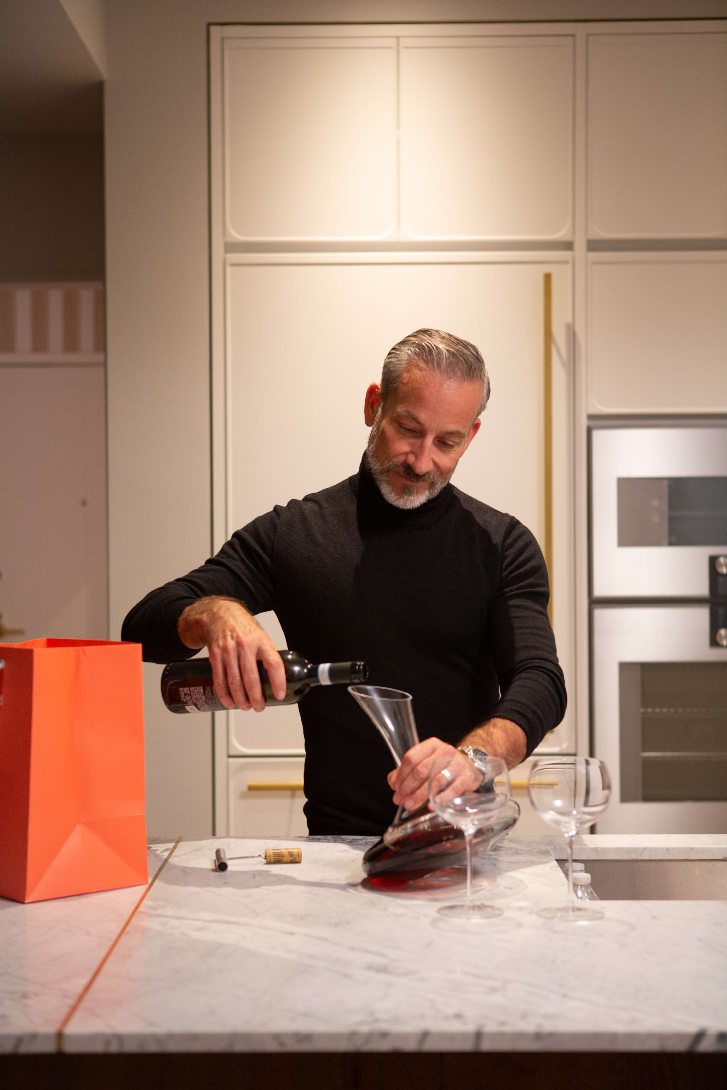 Art husband decanting red wine in his kitchen at 180 E 88th Street, a luxury condominium in the Upper East Side of Manhattan