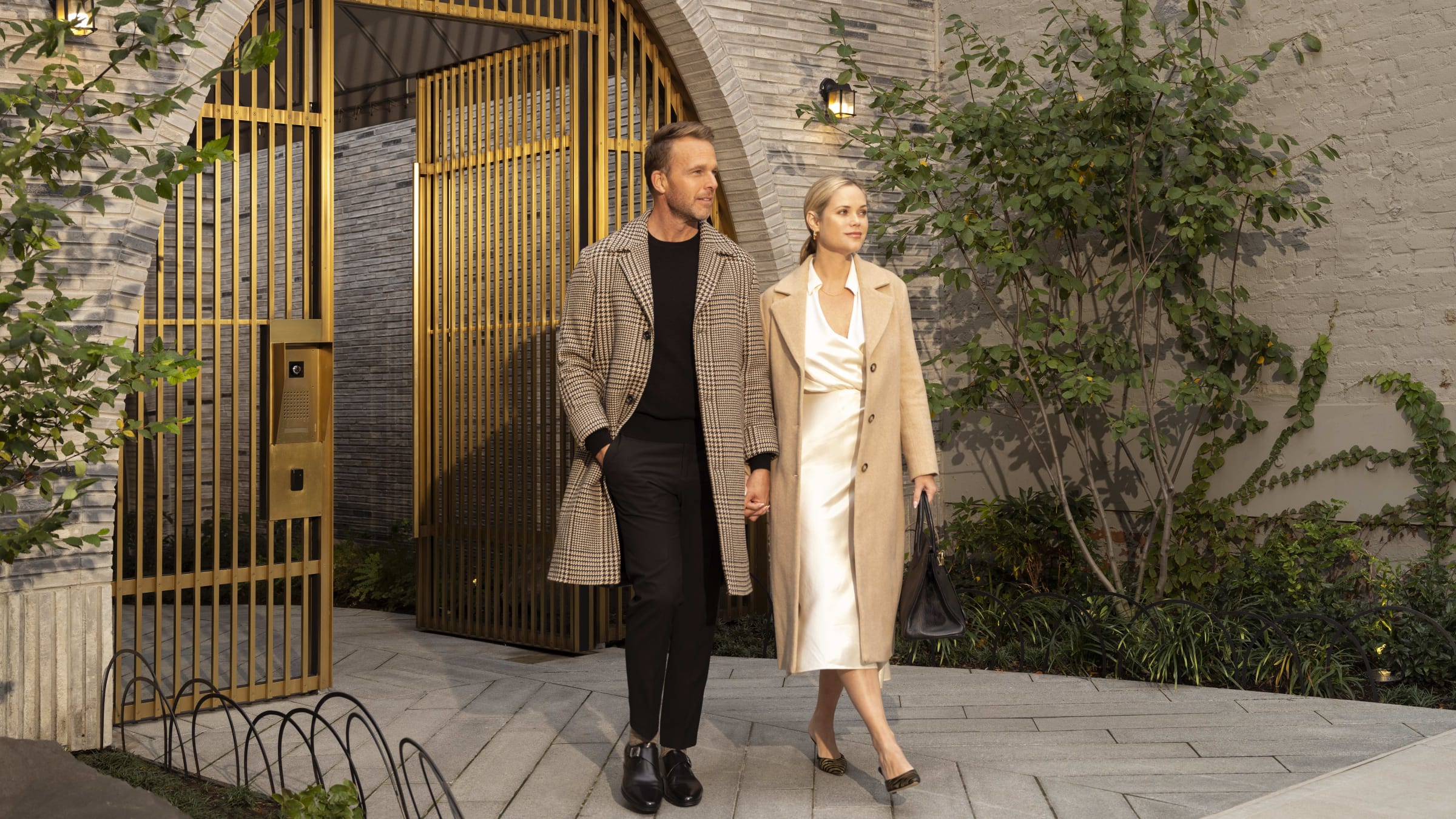 Couple exiting the entrance gates of 180 E 88th Street, a luxury condominium on the upper east side of new york city in manhattan. 